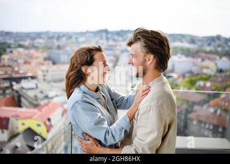 Glückliches junges verliebter Mann, der zu Hause draußen auf dem Balkon steht und sich anschaut. Stockfoto