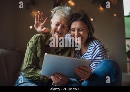 Porträt einer glücklichen älteren Mutter mit einer erwachsenen Tochter im Haus, mit Tablet. Stockfoto