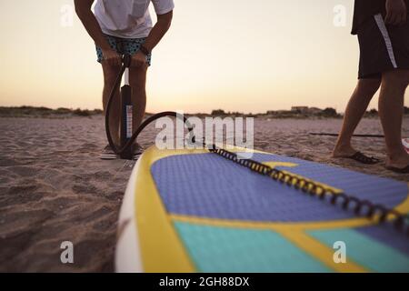 Nahaufnahme des Mannes bereitet sich auf die Paddelsurfen an einem Strand aufblasend supboard Stockfoto