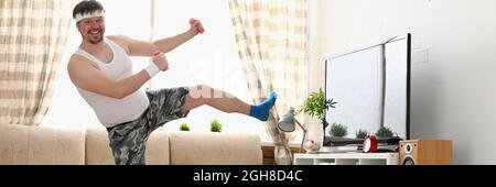 Der dicke Mann in Sportbekleidung und Kurzhanteln macht körperliche Bewegung Stockfoto