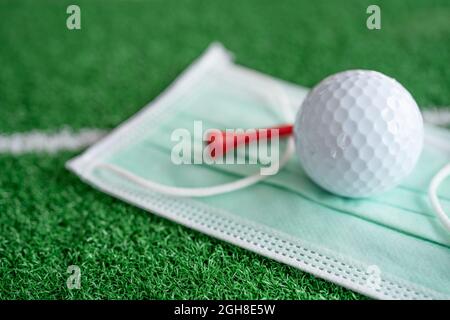 Golfball mit T-Shirt auf Gesichtsmaske zum Schutz des Covid-19-Coronavirus beim Turnier auf dem Golfplatz. Stockfoto