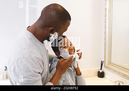 afroamerikanischer Vater mit Sohn, der Spaß mit Rasierschaum im Badezimmer hat Stockfoto