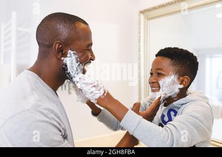 afroamerikanischer Vater mit Sohn, der Spaß mit Rasierschaum im Badezimmer hat Stockfoto