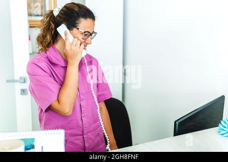 Frau in einer Arztpraxis erhält Anrufe von Patienten - Arzt in einer Zahnklinik macht Termine Stockfoto