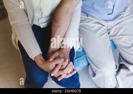 Älteres kaukasisches Paar, das auf dem Sofa sitzt und die Hände hält Stockfoto