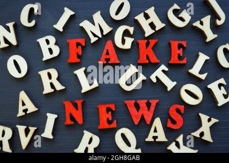 Fake News aus roten Buchstaben und viele Holzbriefe. Stockfoto