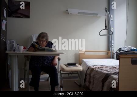 Ältere Frau in der häuslichen Pflege, sitzende Lesung, Paris, Frankreich Stockfoto