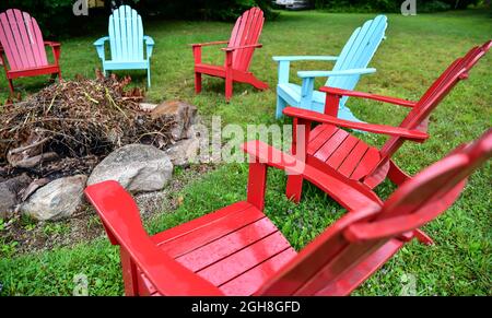 Leere Adirondack-Rasenstühle im Freien entlang der Uferpromenade und dem Strand Stockfoto