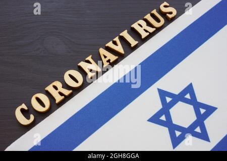 Israelische Flagge und Wort Coronavirus covid-19 auf dem Schreibtisch. Stockfoto
