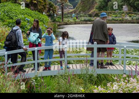 Besucher stehen auf der dekorativen hölzernen Mallard Bridge im spektakulären subtropischen Trebah Garden in Cornwall. Stockfoto