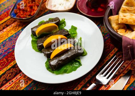 Köstliche umhüllte Weinblätter gefüllt mit Reis serviert mit frischer Zitrone. Traditionelles Gericht Sarma (oder Dolma) in der türkischen Küche Stockfoto