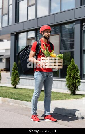 Arabischer Kurier in Schutzhelm-Haltebox mit Gemüse im Freien Stockfoto