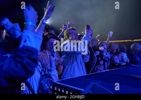 Kiew, Ukraine 3. September 2021: Rückansicht der Menge mit ausgestreckten Armen beim Konzert. Jubelnde Menge beim Rockkonzert. Silhouetten der Konzertmenge Stockfoto