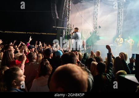 Kiew, Ukraine 3. September 2021: Rückansicht der Menge mit ausgestreckten Armen beim Konzert. Jubelnde Menge beim Rockkonzert. Silhouetten der Konzertmenge Stockfoto