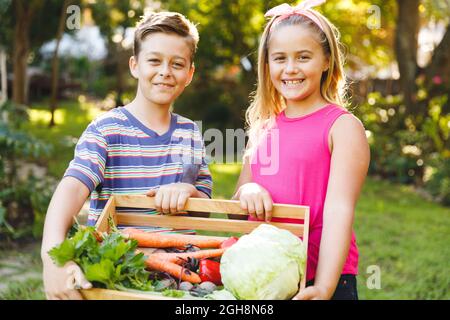 Portrait von glücklichen kaukasischen Bruder und Schwester im Garten mit frischem Bio-Gemüse Stockfoto