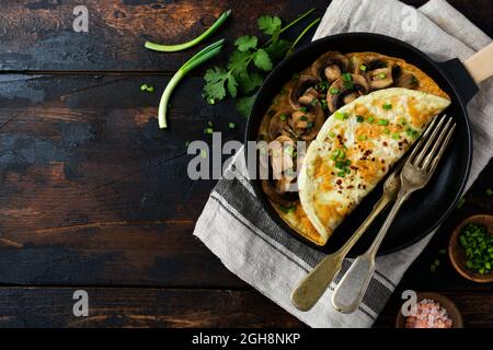 Frisches Rührei, Omelett oder Frittata mit Pilzen, Zwiebeln und frischen Kräutern auf gusseiserner Pfanne. Draufsicht mit Kopierbereich. Stockfoto