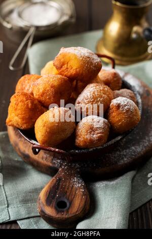 Kleine Donuts. Hausgemachter gebratener Quark in fetten und mit Puderzucker bestreut auf einem Vintage-Teller auf hellem Hintergrund. Selektiver Fokus Stockfoto