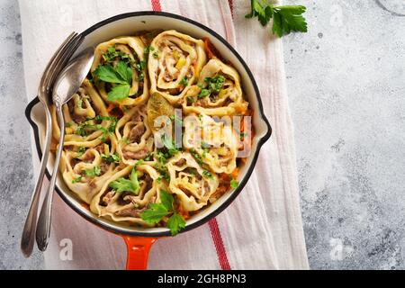 Fleischteig rollt mit Fleisch oder faulen Knödeln in einer gusseisernen Pfanne auf einem alten rustikalen Holzhintergrund. Draufsicht Stockfoto