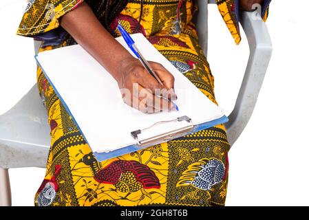 Geschäftsfrau, die Hand sitzt und auf einem Berichtsdokument schreibt Stockfoto