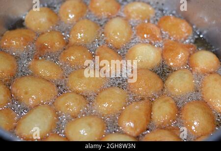 Nahaufnahme von Zalabia, eine Art von gebratenem Teig, ähnlich wie ein Donut, der in kochendem heißem Öl in einer Fritteuse zu Hause brät, ein leckeres Dessert zum Servieren Stockfoto