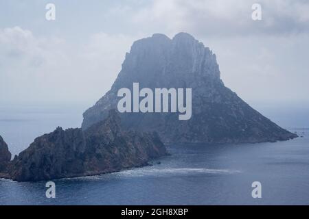 Es Vedrà auf Ibiza mit einem klaren blauen Meer umringt, aufgenommen an einem sonnigen Tag Stockfoto