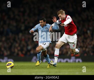 Per Mertesacker von Arsenal zerstoert mit Carlos Tevez von Manchester City während der Barclays Premier League zwischen Arsenal und Manchester City am 13. Januar 2013 im Emirates Stadium in London. David Klein Stockfoto