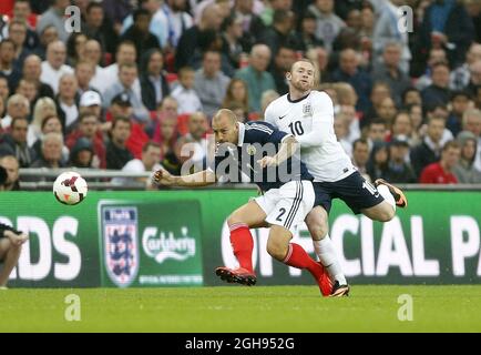 Der englische Wayne Rooney tünchelt mit dem schottischen Alan Hutton beim Freundschaftsspiel Vauxhall International zwischen England und Schottland, das am 14. August 2013 im Wembley Stadium in London, Großbritannien, stattfand. Stockfoto