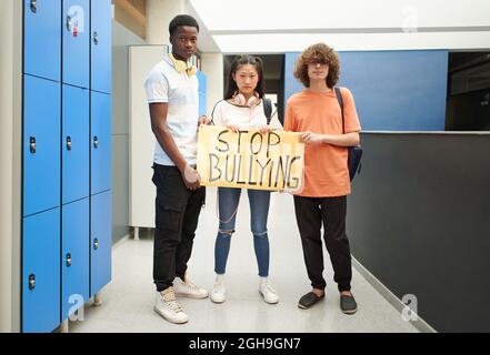 Rassisch unterschiedliche Studentengruppen demonstrieren gegen Mobbing. Ältere Schüler schauen auf die Kamera, während sie für Gleichberechtigung arbeiten. Stockfoto