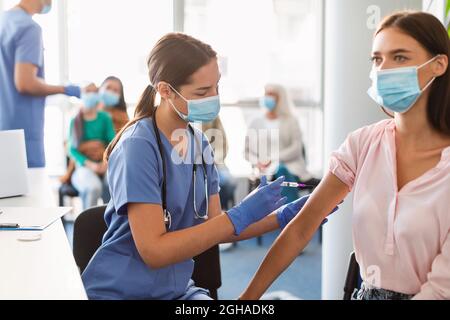 Lady Erhält Coronavirus-Impfstoff Injektion Sitzt Mit Arzt Stockfoto