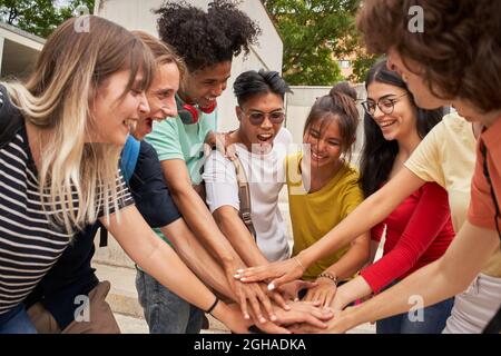 Eine Gruppe von Teenagerfreunden, die sich gegenseitig hoch-fiving, glücklich und motiviert, eine gute Zeit zusammen. Konzept von Freundschaft und Jugend. Stockfoto