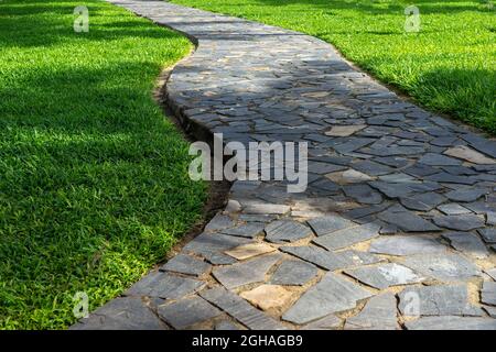 Garten winkender Steinweg zwischen grünem Rasen. Stadtpark Landschaftsgestaltung. Stockfoto