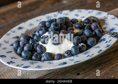 Skyr mit frischen Blaubeeren, isoliert auf einem Holztisch Stockfoto