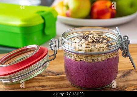Frühstück zum Mitnehmen. Blaubeerjoghurt mit Hafer und Chiasamen in einem Glasgefäß Stockfoto