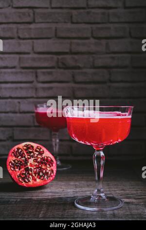 Cocktail "Barbotage" aus Grenadinsirup, Orangensaft und Sekt, serviert in Vintage-Champagner-Coupé-Gläsern, mit der Hälfte des Granatapfels. Stockfoto