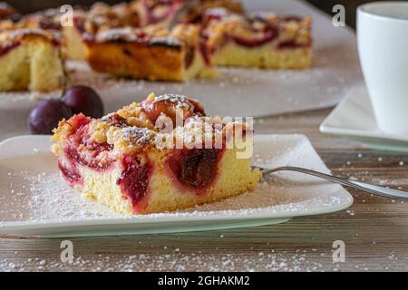 Pflaumenkuchen auf weißem Teller mit Gabel auf einem Kaffeetisch. Stockfoto