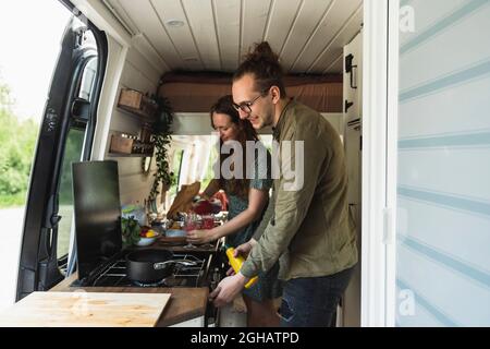 Heterosexuelles Paar, das während des Urlaubs im Campingbus Essen vorbereitet Stockfoto