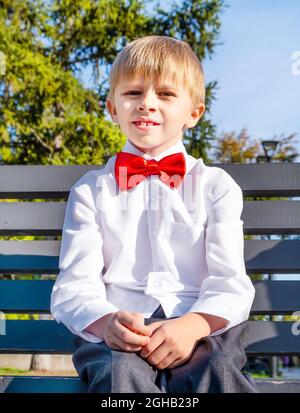 Porträt eines kleinen Jungen auf der Bank im Sommerpark Stockfoto