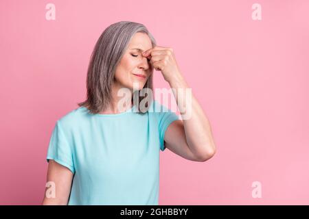 Foto von traurigen älteren grauen Frisur Dame Hand Kopf tragen blaue Bluse isoliert auf rosa Hintergrund Stockfoto
