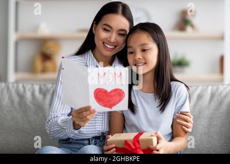 Glücklich asiatische liebevolle Tochter Gruß Mutter mit Muttertag, junge Frau halten und lesen handgemachte Karte Stockfoto