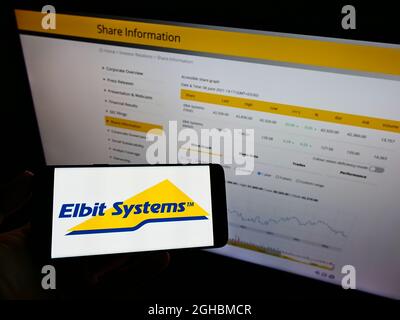 Person, die das Smartphone mit dem Logo der Firma Elbit Systems Ltd. Auf dem Bildschirm vor der Website hält. Stockfoto