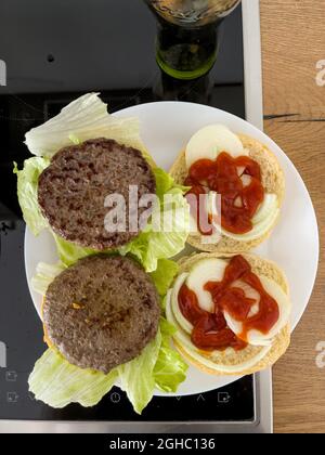 Blick von oben auf ein frisch verzehrfertiges, gebratenes Paar Hamburger, leckere zubereitete Speisen von zu Hause. Stockfoto