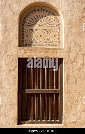 Hölzerne arabische Stil Bogen Fensterportal in Steinmauer mit Ornamenten, traditionelle arabische Architektur, Al Fahidi, Dubai, Vereinigte Arabische Emirate. Stockfoto