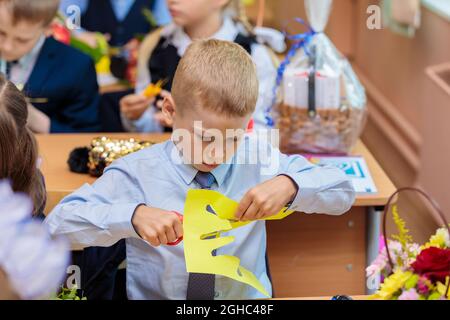 Erstklässler in der Lektion schneiden Zahlen für Anwendungen aus Papier aus. Schule, Wissenstag. Moskau, Russland, 1. September 2021 Stockfoto