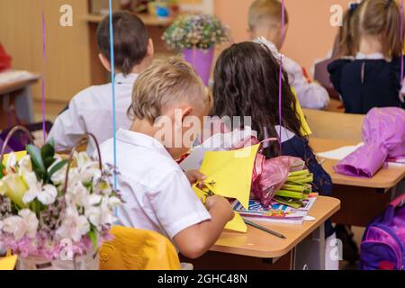 Erstklässler in der Lektion schneiden Zahlen für Anwendungen aus Papier aus. Schule, Wissenstag. Moskau, Russland, 1. September 2021 Stockfoto