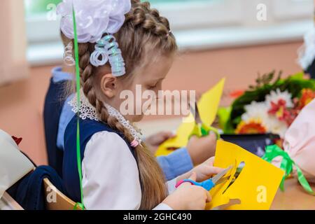 Erstklässler in der Lektion schneiden Zahlen für Anwendungen aus Papier aus. Schule, Wissenstag. Moskau, Russland, 1. September 2021 Stockfoto