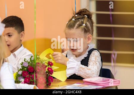 Erstklässler in der Lektion schneiden Zahlen für Anwendungen aus Papier aus. Schule, Wissenstag. Moskau, Russland, 1. September 2021 Stockfoto