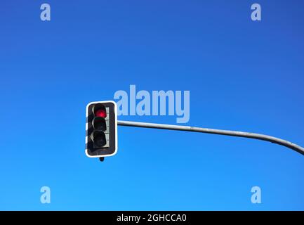 Detail einer Ampel mit dem roten Licht an und dem blauen Himmel im Hintergrund Stockfoto