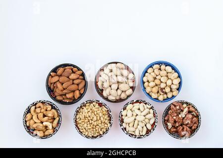 Verschiedene Arten von Nüssen: Erdnüsse, Pinienkerne, Cashewkerne, Mandeln, Haselnüsse, Walnüsse und Pistazien auf weißem Hintergrund. Draufsicht. Speicherplatz kopieren Stockfoto