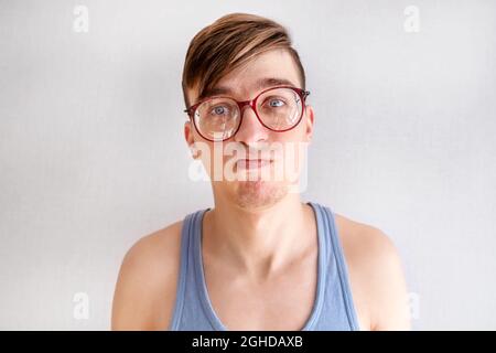 Trauriger junger Mann im Unterhemd an der weißen Wand Nahaufnahme Stockfoto