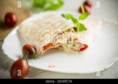 Gebackene Pita Rolle mit Füllung in einem Teller auf einem Holztisch Stockfoto